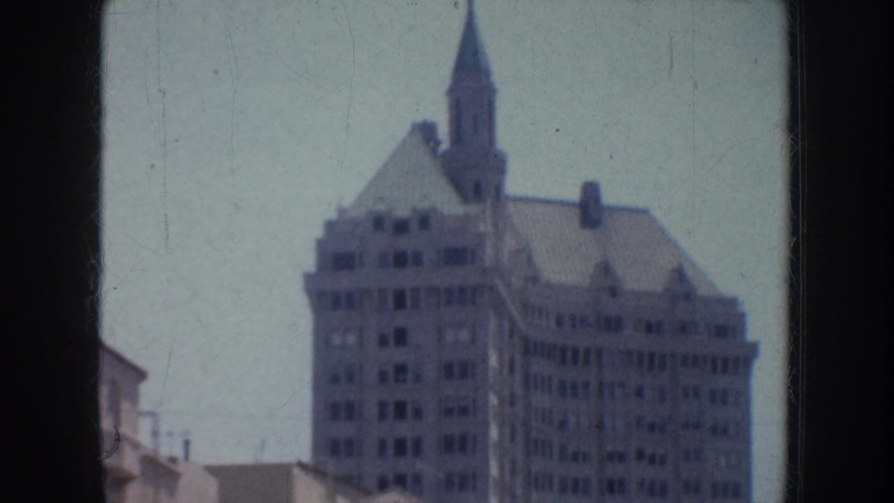 Ornate multi-story building with a pointed spire above nearby rooftops.
