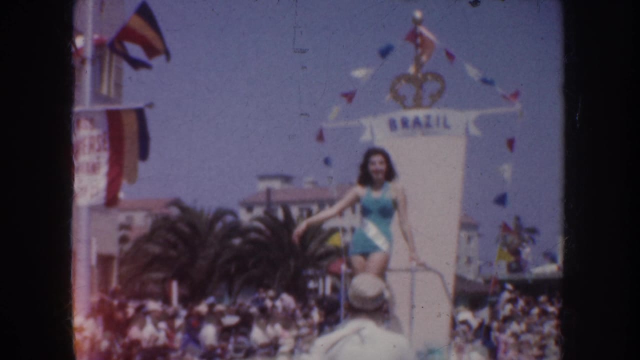 1952 California parade view of the Brazil float, showing the performer on the platform, pennant flags, palm trees, and spectators.