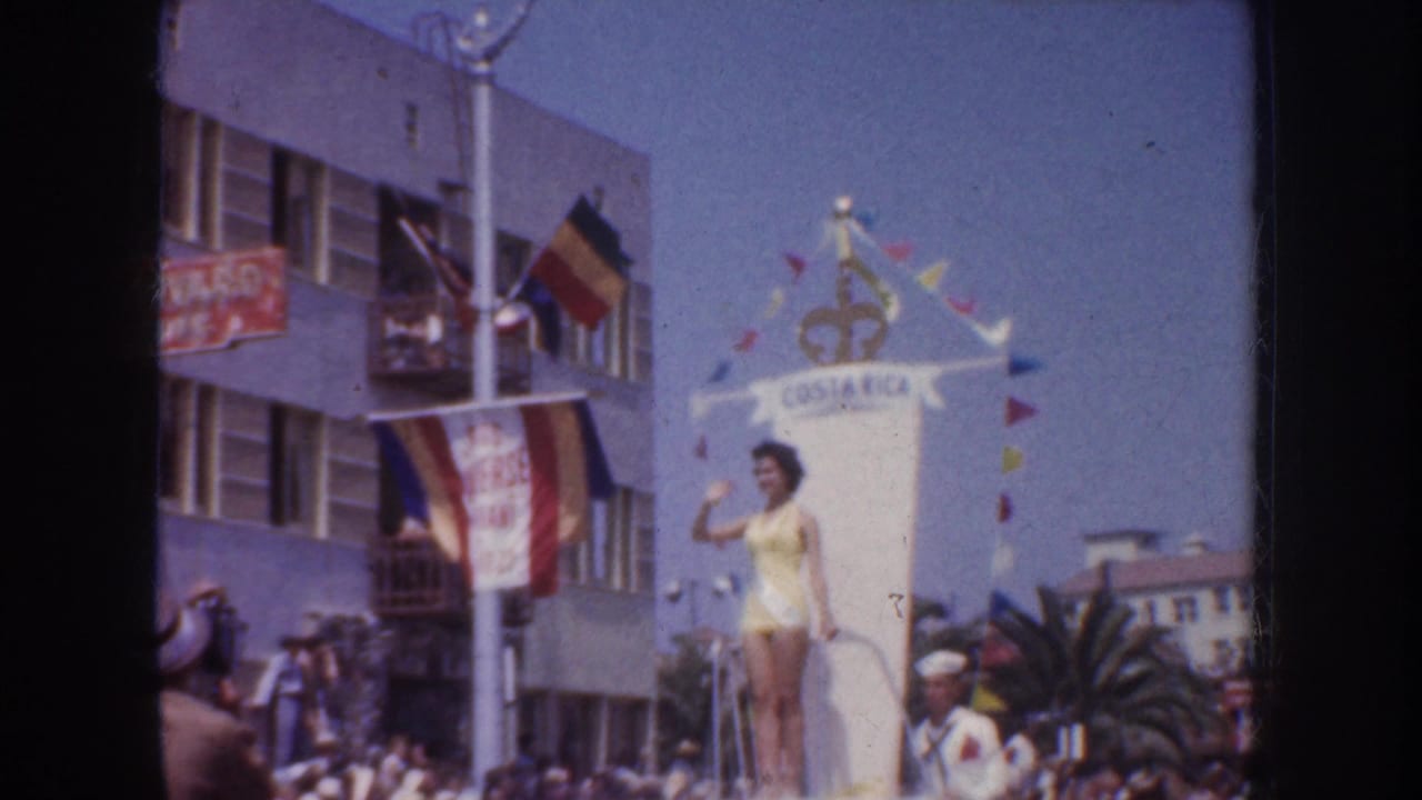 A woman in a yellow swimsuit waves from a decorated float during the 1952 California parade scene.