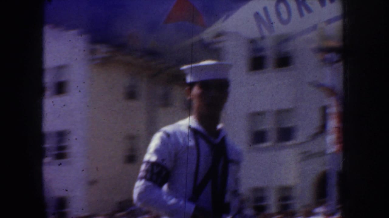 1952 California home-movie frame showing a sailor in white uniform near a building marked NORWAY, partly obscured by film gate edges.