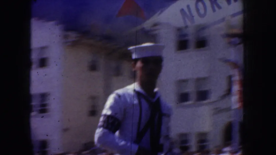 1952 California home-movie frame showing a sailor in white uniform near a building marked NORWAY, partly obscured by film gate edges.