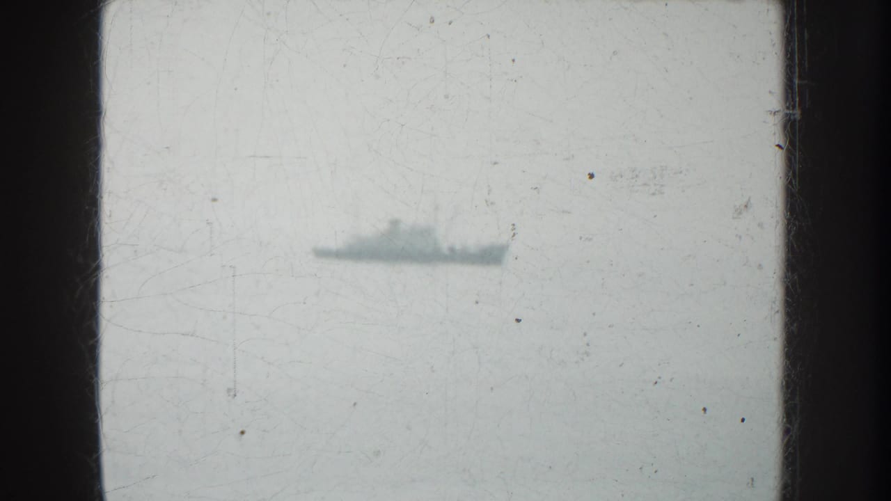 Distant vessel on the water in 1952 California home-movie footage, with soft focus, scratches, and dark frame edges.