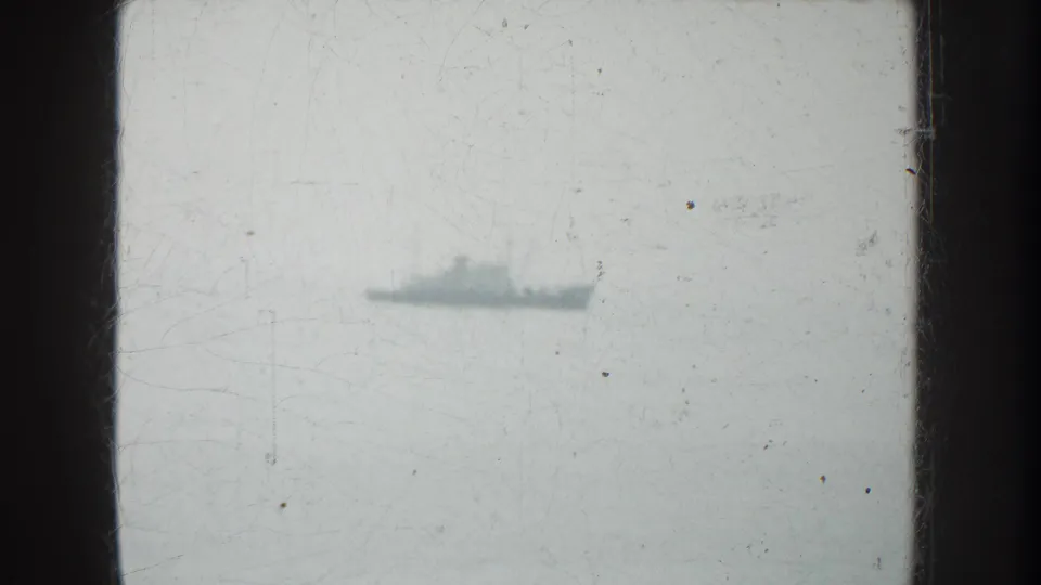Distant vessel on the water in 1952 California home-movie footage, with soft focus, scratches, and dark frame edges.