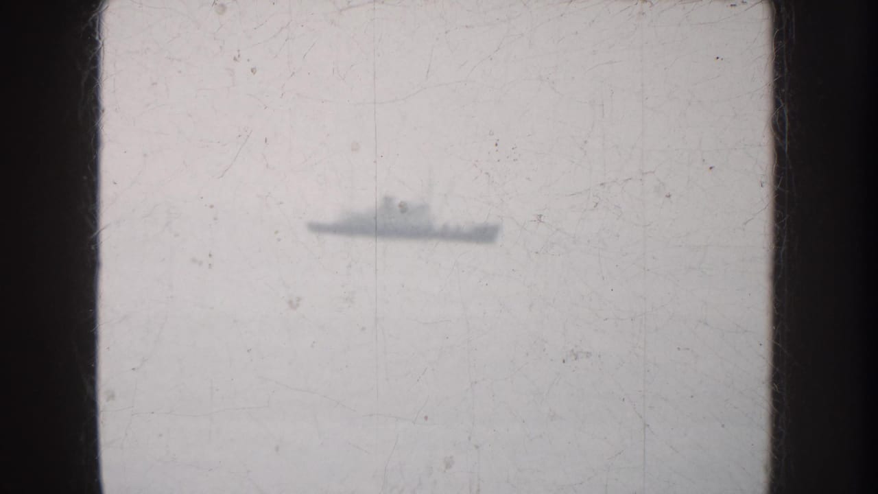 Small ship silhouette on a pale horizon with visible film wear.