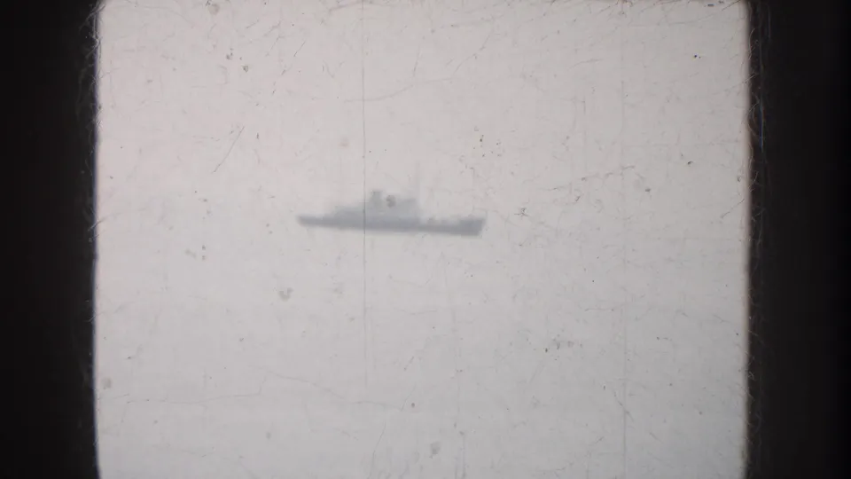 A small, distant ship profile crosses the horizon in archival 8mm footage from California, with grain and scratches visible.