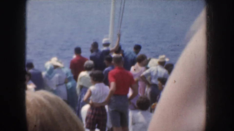 Passengers in mid-century clothing stand and sit on a boat deck near calm blue water in California, supported by the clip metadata.