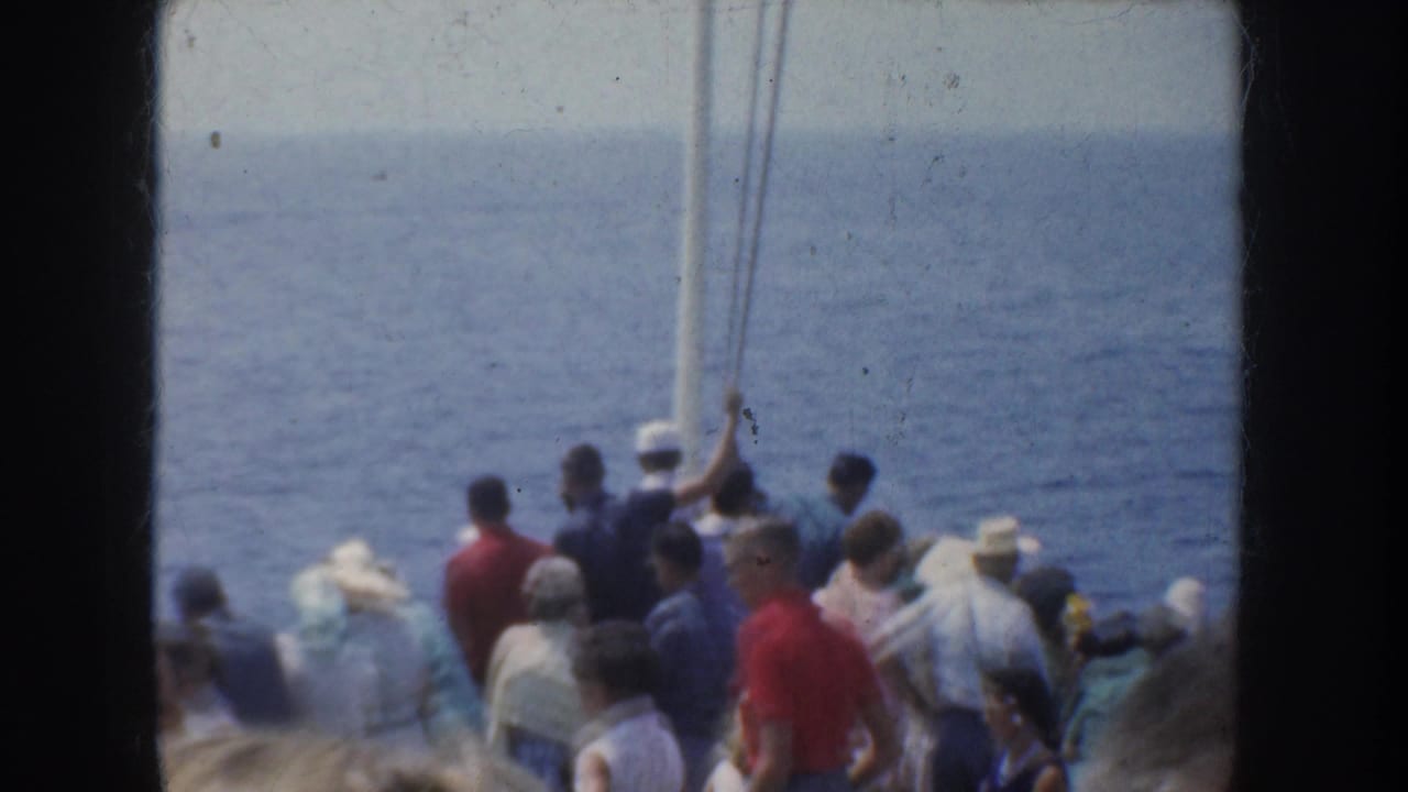 1952 California home-movie frame showing passengers in casual clothing gathered on a ship deck near the open blue sea.