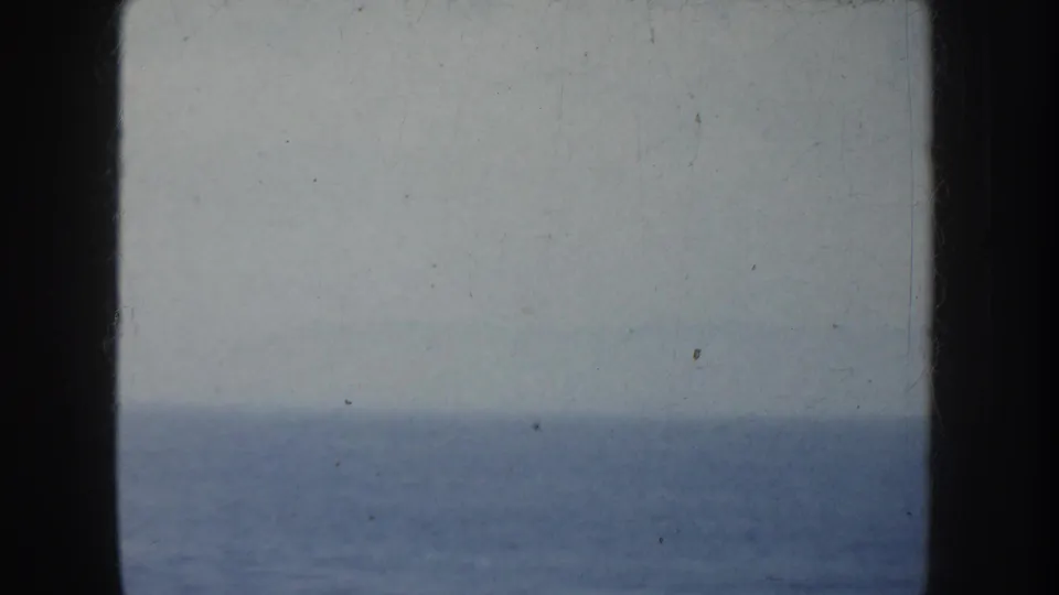 Soft 8mm view of the open ocean from the ship, with the horizon low in frame and dark vertical borders at the sides.