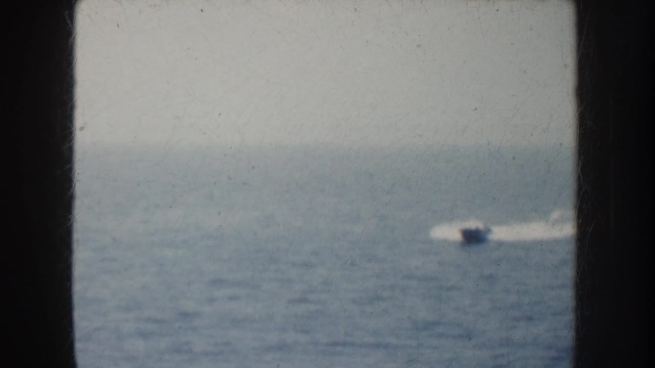 1952 California home-movie frame showing a small speedboat and white wake seen through a dark ship window or opening.