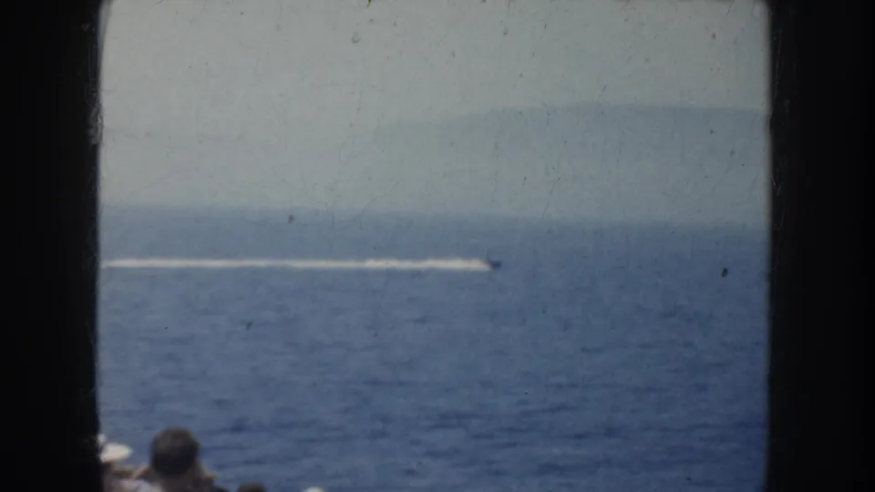 1952 California home-movie frame showing a small speedboat leaving a white wake across open blue water.