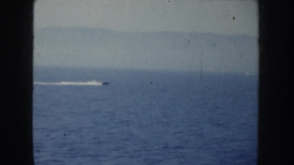 Home-movie view of a speedboat wake across open California water, partially bordered by dark foreground structure.