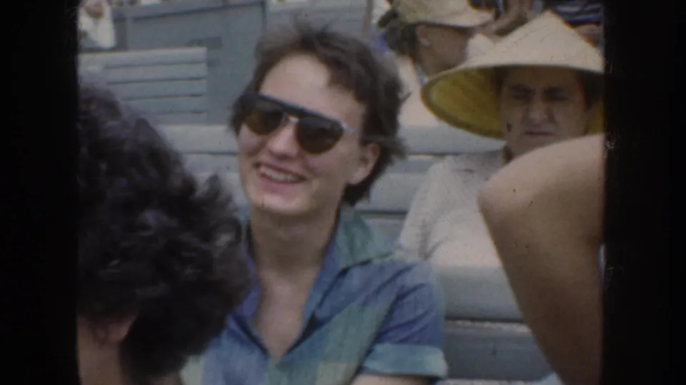 1952 California home-movie frame with spectators, including a smiling woman in sunglasses and a man in a straw hat.