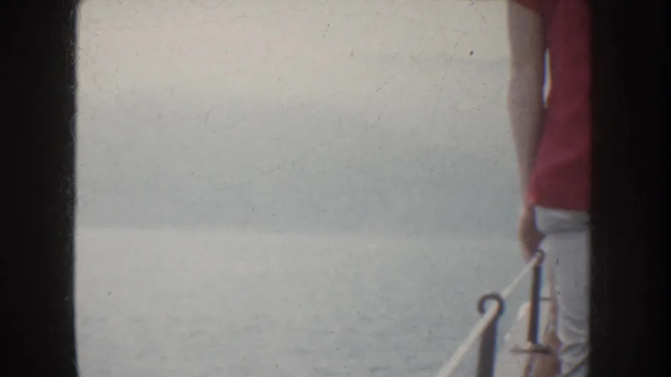 1952 California boat-ride frame showing water beside the vessel, with a partial standing passenger and railing at the edge.