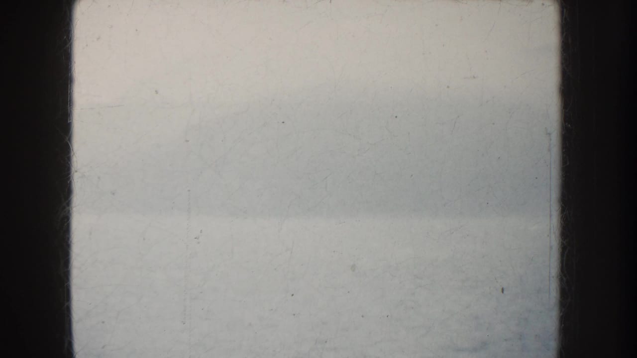 Foggy California water view from an 8mm home movie, with calm surface, faint landform, and dark boat structure at the sides.