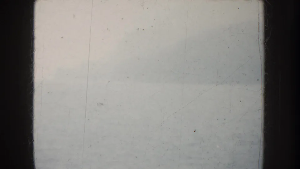 Soft 8mm view of foggy California water with faint mountain or shoreline silhouettes and dark boat structure along the frame edges.
