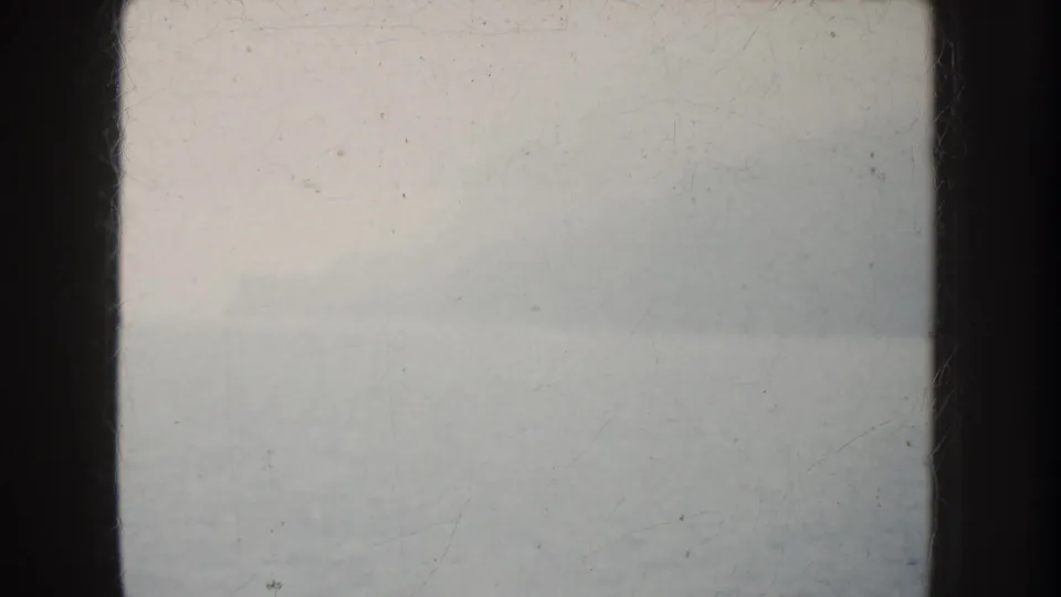 Overexposed 1952 California 8mm frame showing a pale ocean horizon through dark vertical framing, with film scratches visible.