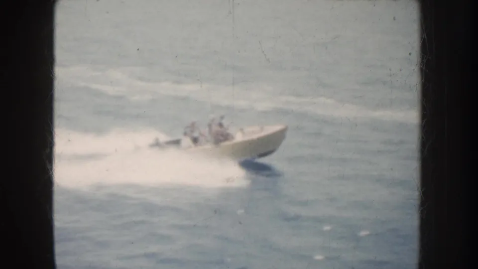 A small motorboat carrying passengers speeds across California water, with a bright wake and soft 8mm motion blur.
