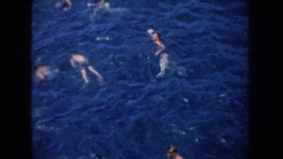 1952 California 8mm frame showing several swimmers spread across clear blue lake water during a sunny leisure scene.