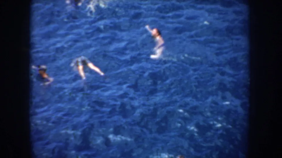 1952 California home-movie frame of swimmers in blue lake water, with one person raising an arm and others floating nearby.