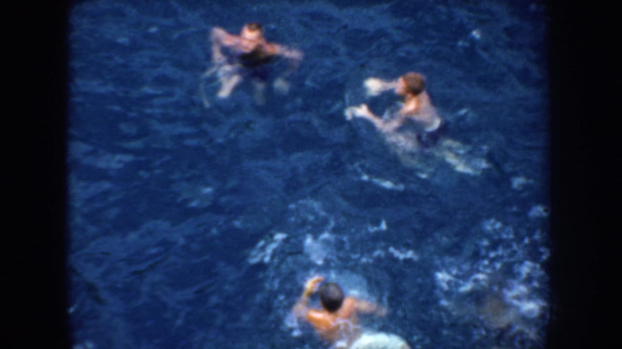 High-angle 1952 California ocean scene with male swimmers treading water and splashing in saturated blue 8mm footage.