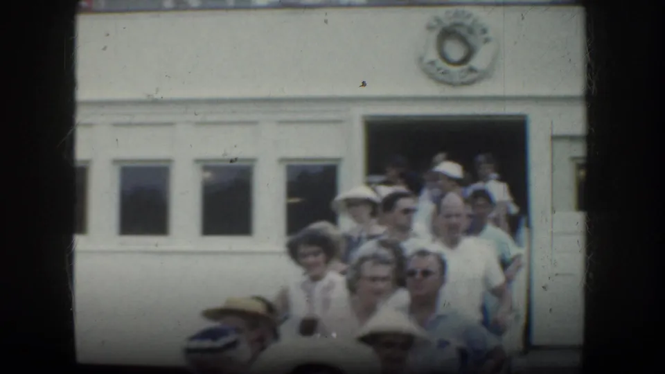 1952 California 8mm frame showing a crowd descending steps beside a white vessel or building exterior, with faces and hats visible.