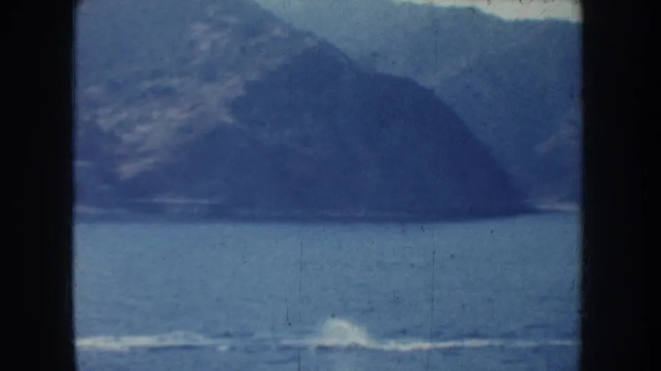 The camera holds on blue water and hazy California shoreline, with a boat wake crossing the lower frame.