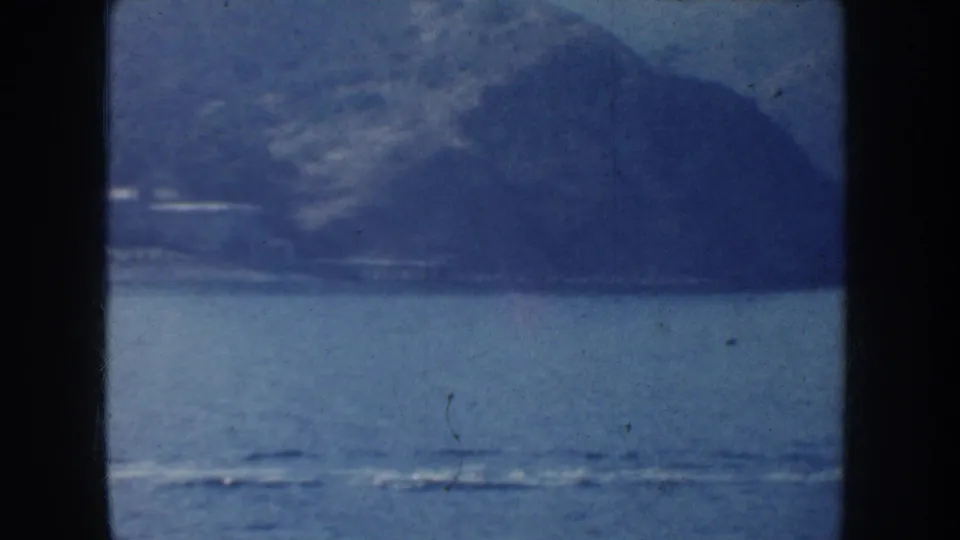 A wide 1952 California coastal view shows water, wake lines, and hazy mountains with the boat now distant or out of frame.