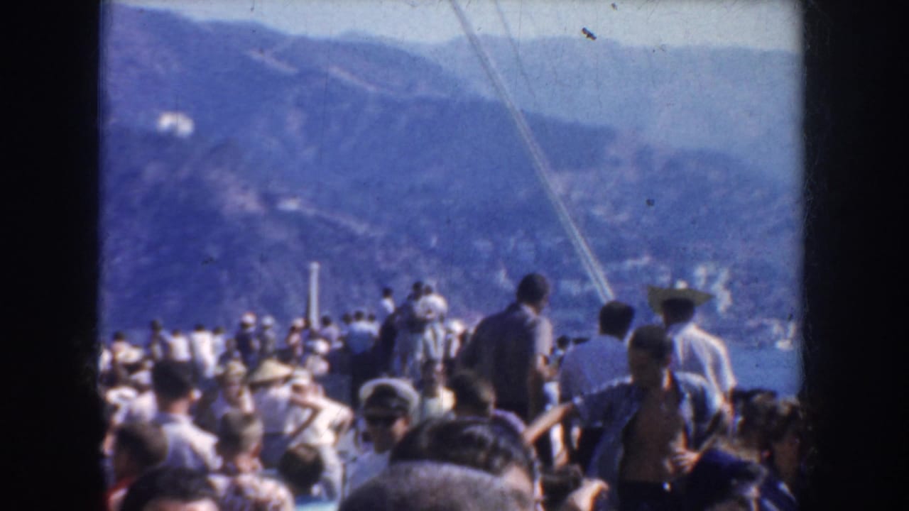 1952 California 8mm frame showing passengers on a crowded boat deck looking toward water and distant mountains.