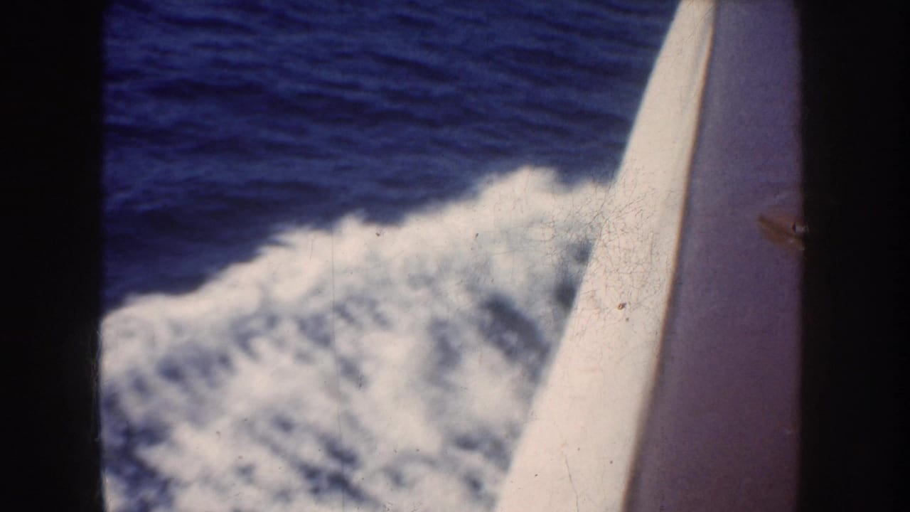 1952 California-associated 8mm frame looking past a boat edge at blue ocean water and a foaming wake.