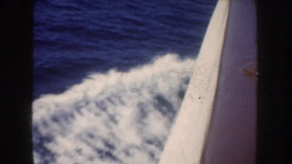 1952 California-associated 8mm frame looking past a boat edge at blue ocean water and a foaming wake.