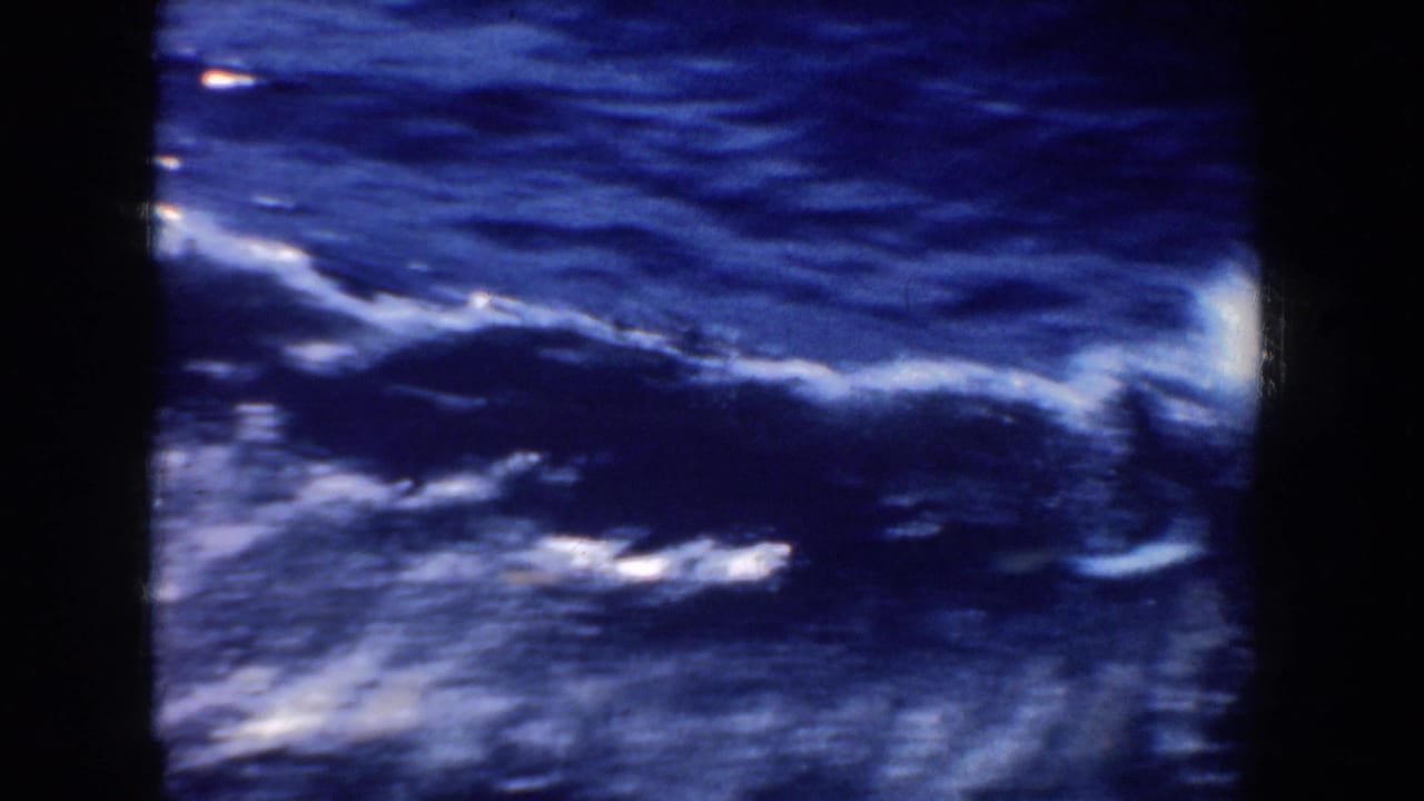 1952 California 8mm frame showing dark blue ocean water, white foam, and spray viewed from a moving boat through vertical framing.