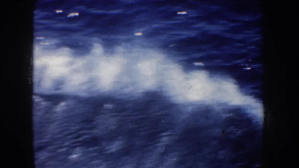1952 California 8mm view of churning ocean foam and blue water, filmed from a moving vessel with dark framing visible.
