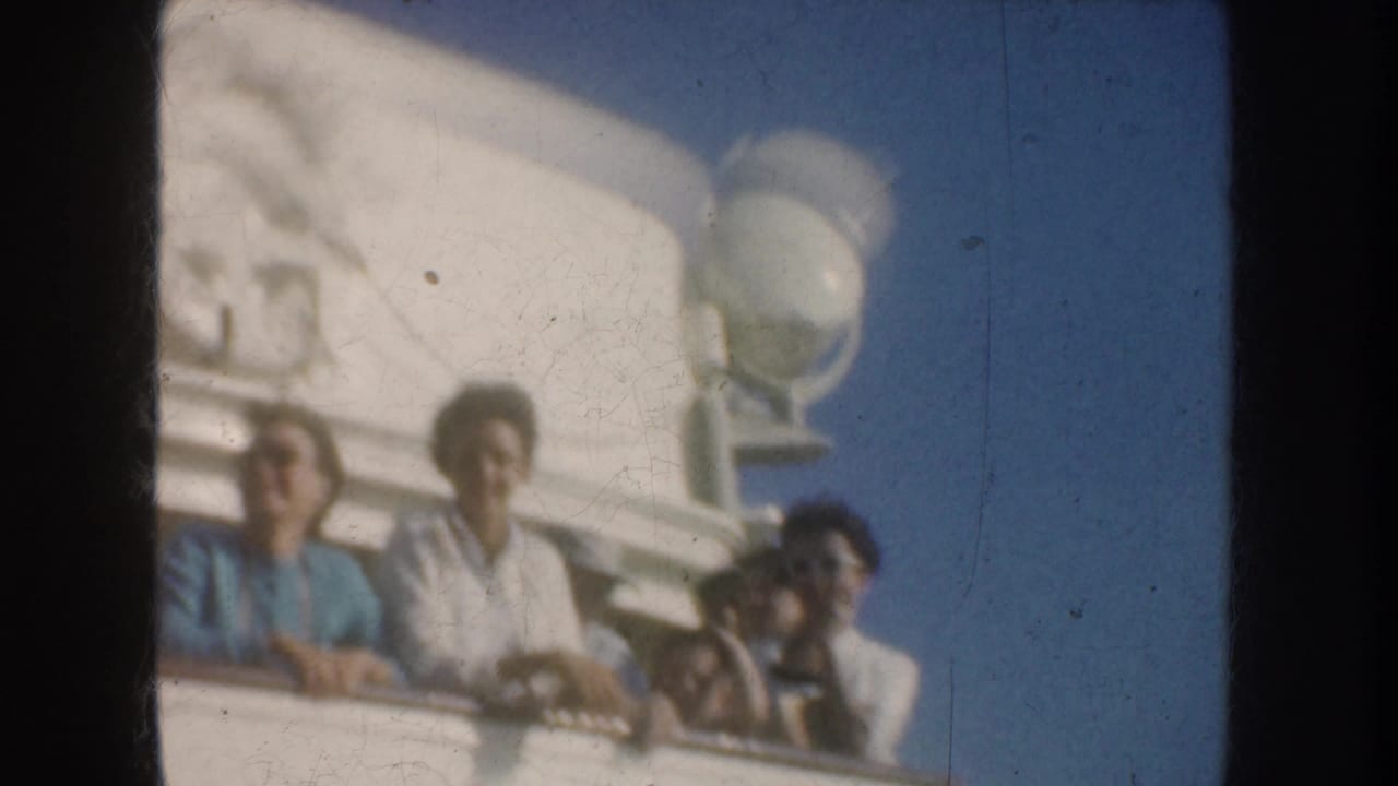 1952 California 8mm frame showing adults on a vessel deck, with a white ship structure and wheel emblem partly visible above them.