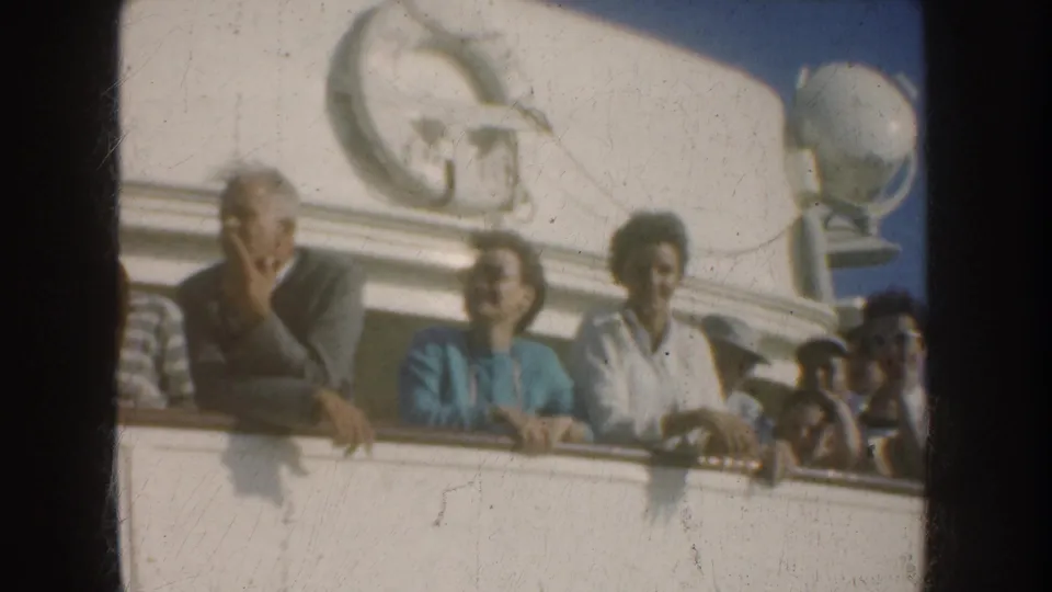 1952 California harbor footage frame with several adults leaning at a vessel railing below a prominent ship-wheel emblem.