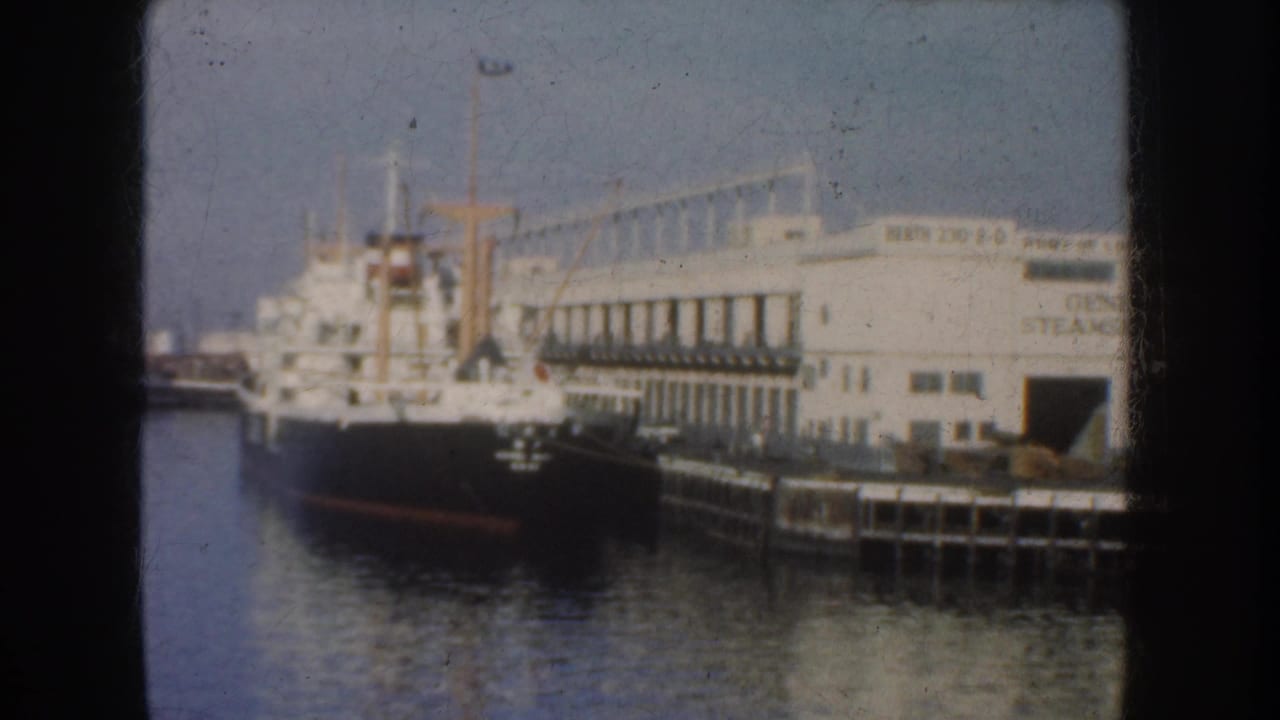 1952 California 8mm frame showing a large cargo ship moored beside a white dock building marked General Steamship.