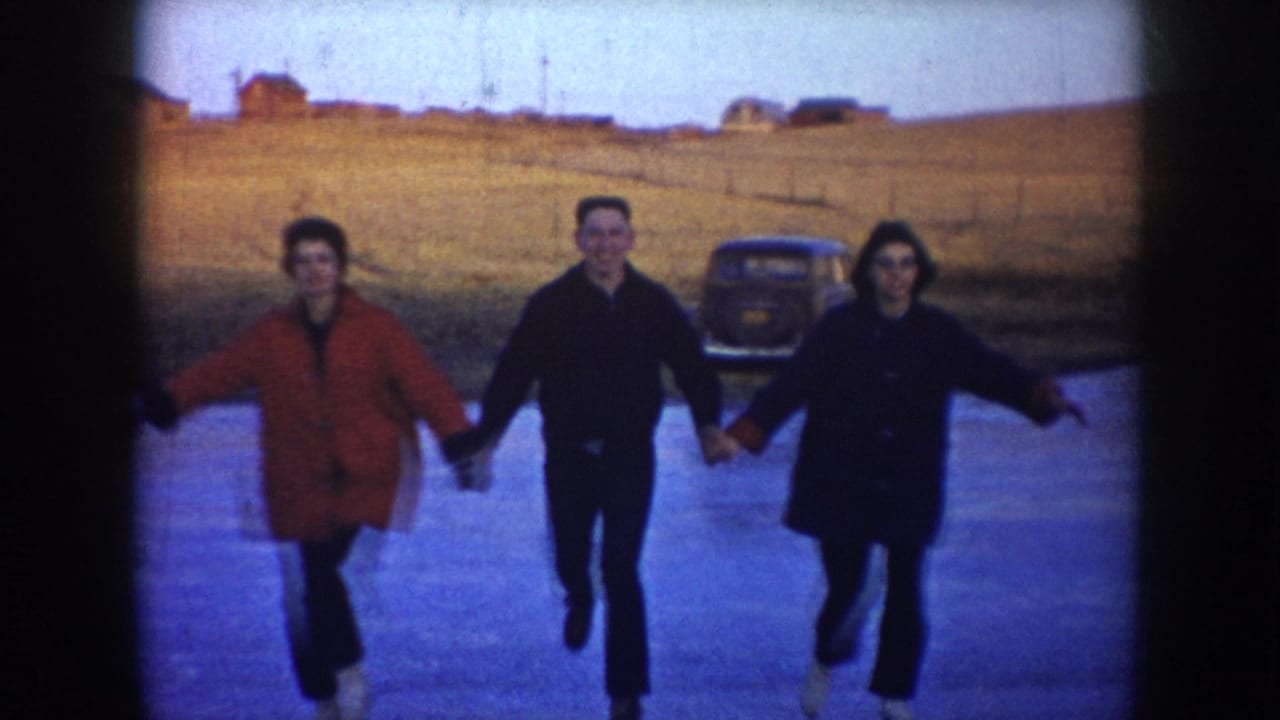 Three skaters approach the camera while holding hands on the ice.