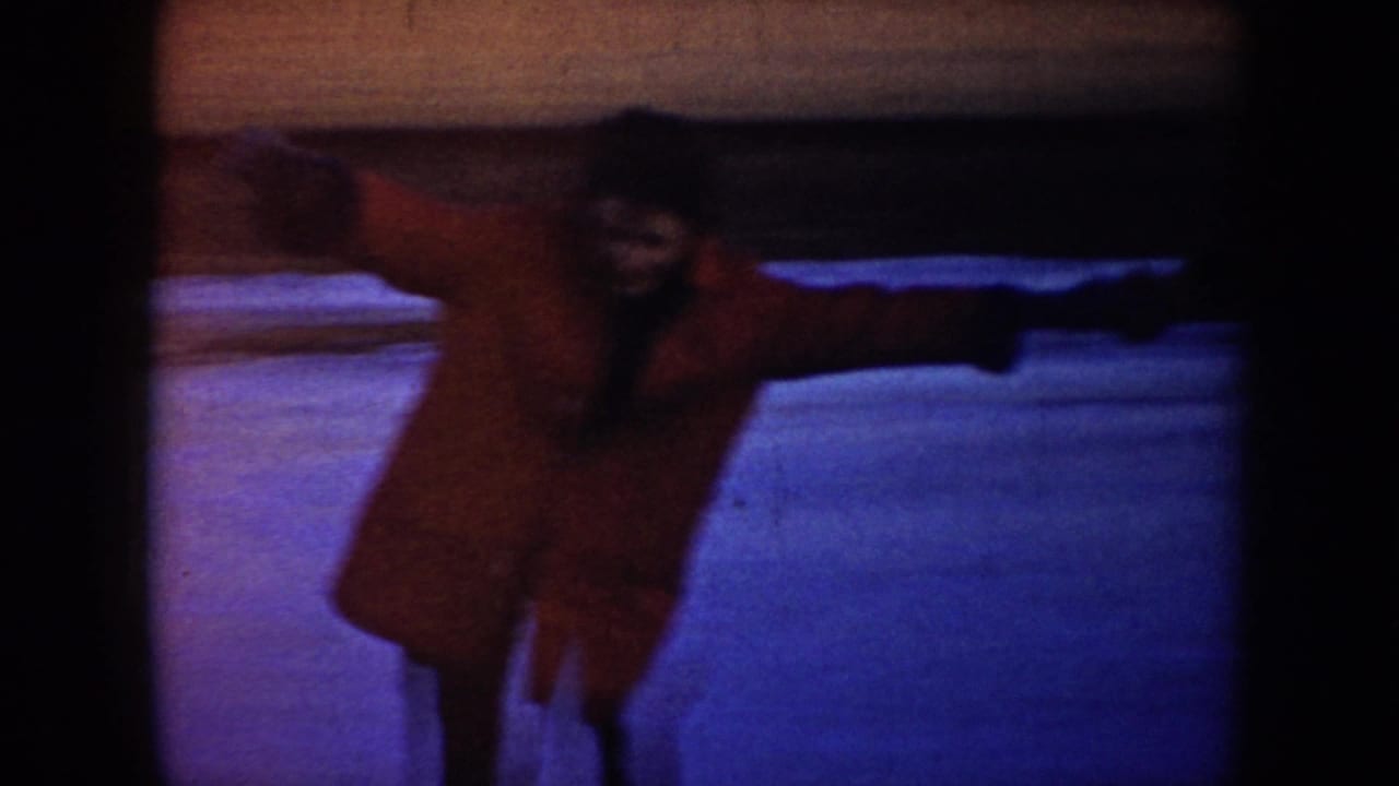 A skater in a red coat glides with arms outstretched on the ice.