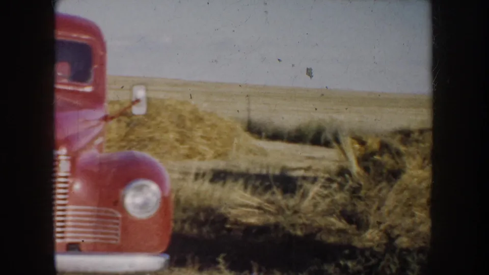 A red vintage truck appears beside the man and horse in the South Dakota field, suggesting a rural farm or ranch setting.