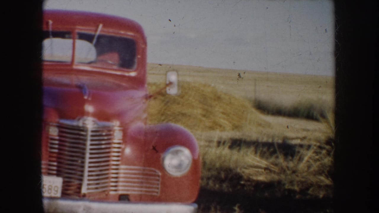 1953 South Dakota 8mm frame showing a red vintage pickup facing the camera in open prairie grass.
