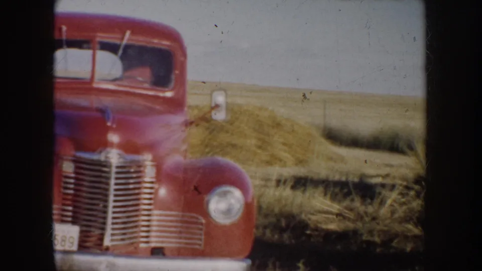1953 South Dakota 8mm frame showing a red vintage pickup facing the camera in open prairie grass.