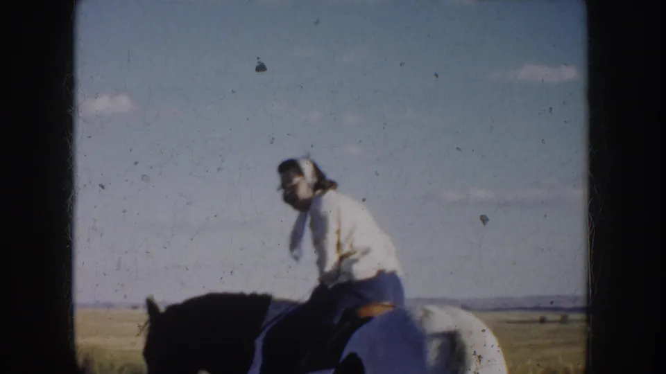 The rider sits on the pinto horse in the South Dakota prairie setting, with the open horizon behind her.