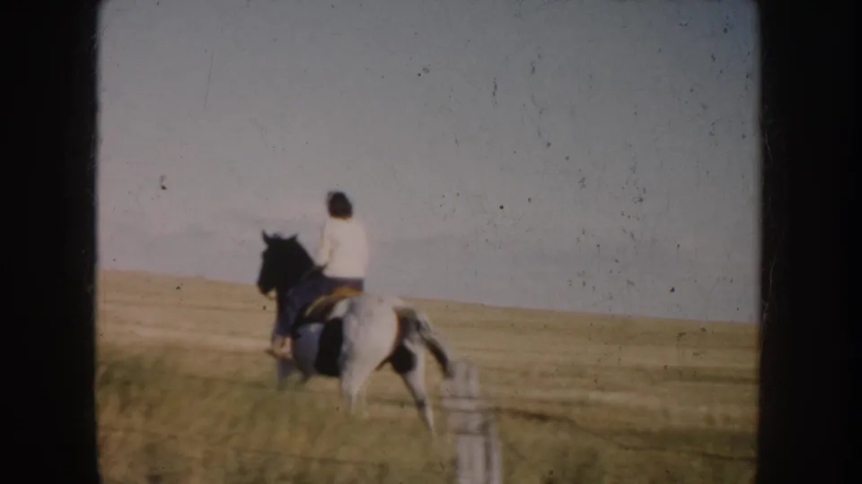 South Dakota prairie view with a rider on a pinto horse traveling away from the camera in 1953 home-movie footage.