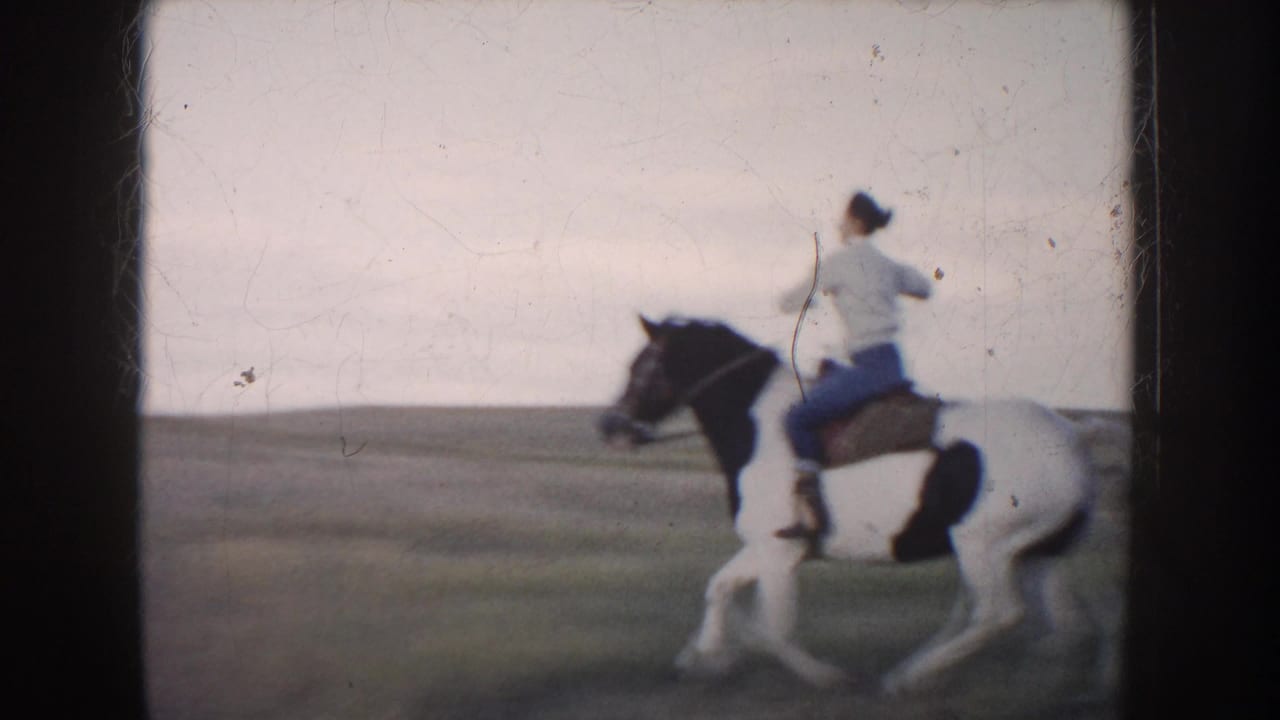 1953 South Dakota 8mm frame with a rear view of a rider on a pinto horse moving through an open field.