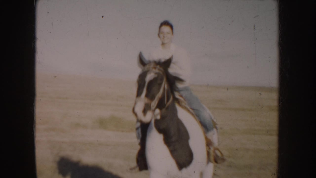 A front-facing view shows the young rider smiling while mounted on the pinto horse in the rural South Dakota field.