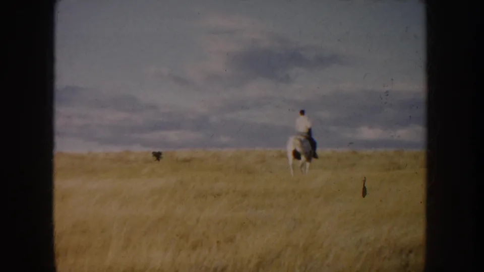 A distant rider on a dark-and-white horse crosses the open South Dakota field in this 1953 8mm frame.