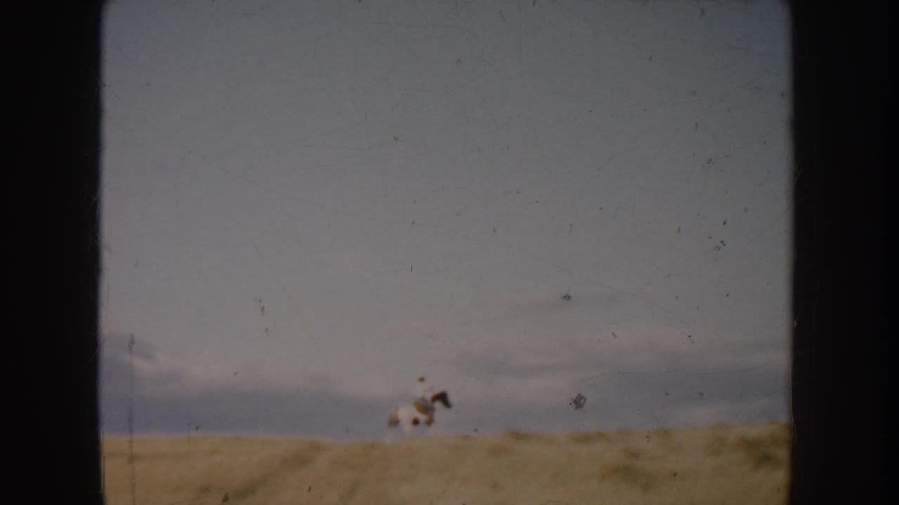 The final frame shows the rider and white horse farther across the South Dakota field, reduced to a small moving figure in the landscape.