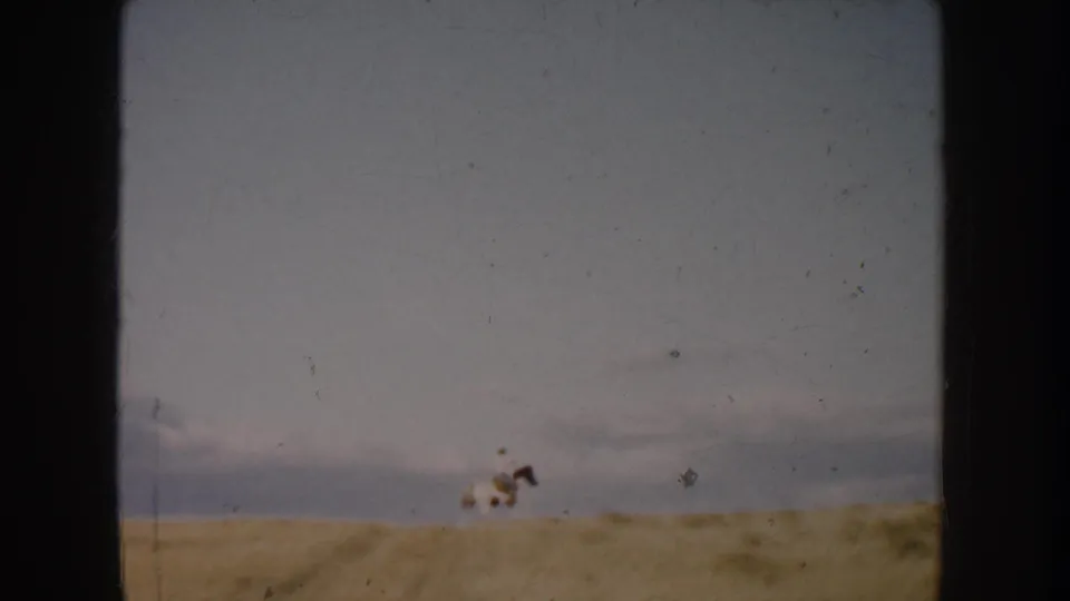 The final frame shows the rider and white horse farther across the South Dakota field, reduced to a small moving figure in the landscape.