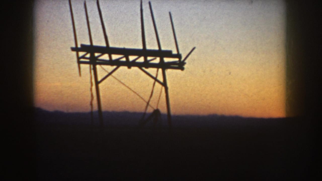 1953 South Dakota home-movie frame showing a silhouetted television antenna structure against an orange-blue rural sunset.
