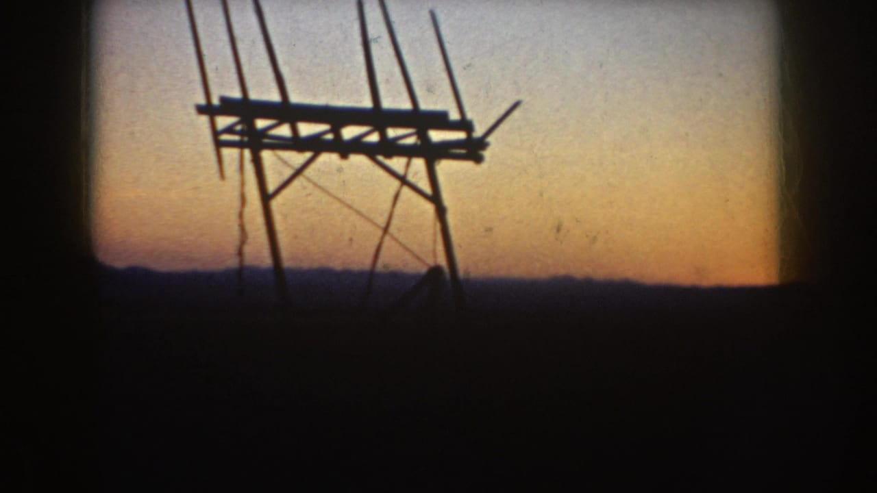 Silhouetted antenna frame and rods in front of a fading orange and blue sky.