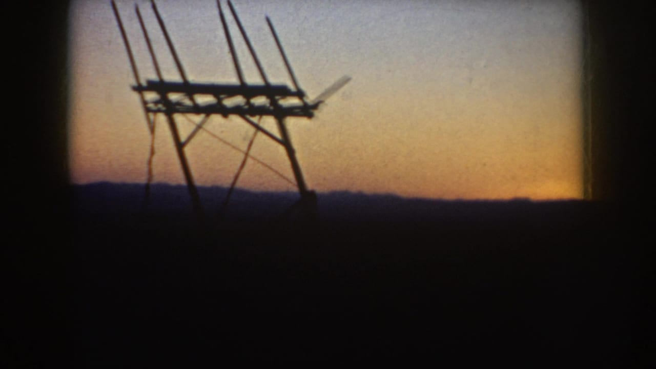 1953 South Dakota 8mm frame showing a silhouetted wooden antenna-like structure against a fading orange sunset sky.